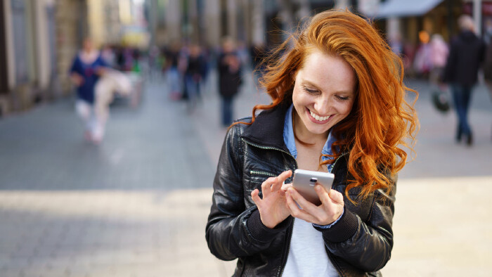 Fröhliche Frau tippt in ihr Handy