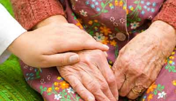 Pflegerin hält die Hand einer alten Pensionistin.