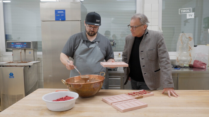 Christoph Haag, der Gesch&auml;ftsf&uuml;hrer der "Tiroler Edlen" beim R&uuml;hren der Schokolade in der K&uuml;che, Moderator Hubsi Trenkwalder schaut ihm &uuml;ber die Schulter