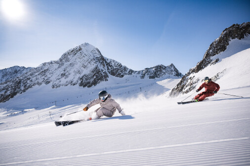 Zwei Personen carven auf der leeren Skipiste hinunter