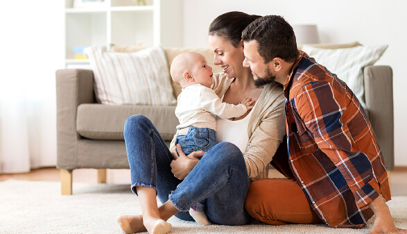 Junge Familie mit Kleinkind sitzt im Wohnzimmer