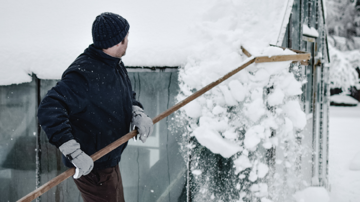 Mann entfernt Schneewechten vom Hausdach