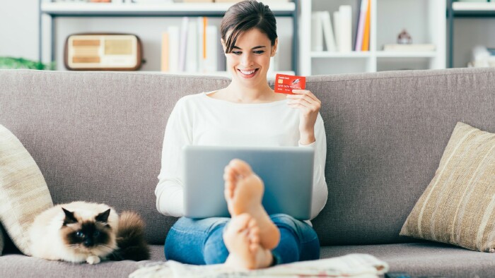 Frau sitzt am Sofa und kauft online etwas ein