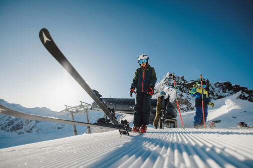 Drei Personen schnallen sich auf der Kaunertaler Bergstation die Ski an
