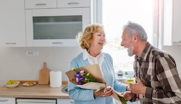 Älteres Ehepaar steht in der Küche und lacht gemeinsam. © Canva
