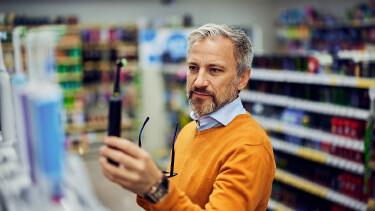 Mann steht im Handel und h&auml;lt eine elektrisch Zahnb&uuml;rste in der Hand