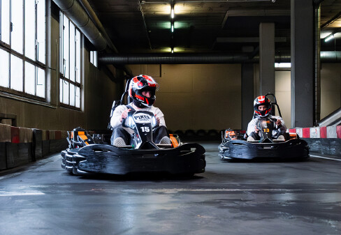 2 Besucher:innen sitzen in Karts und nutzen die Kartbahn im B1