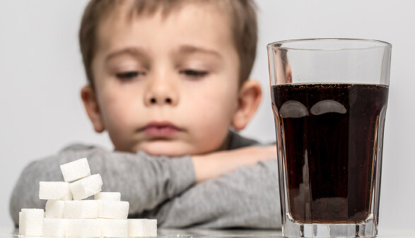 Kind sitzt vor Limonade und W&uuml;rfelzucker