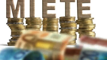 Geldscheine und aufgetürmte Münzen, darauf stehen die Holz-Buchstaben MIETE