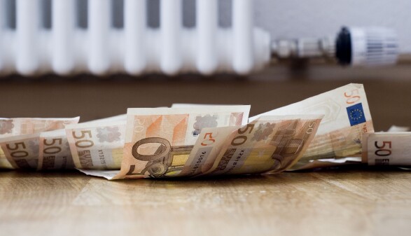 Im Hintergrund sieht man den unteren Teil eines Heizk&ouml;rpers mit Thermostat, davor liegen am Boden ca. 10 50-Euro-Scheine