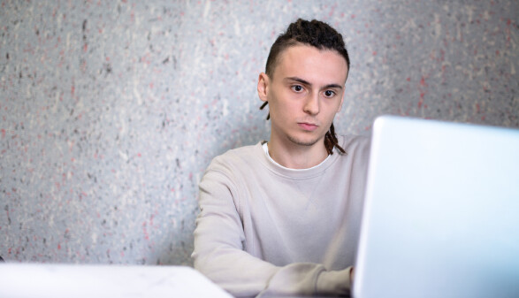 Junger Mann arbeitet konzentriert am Laptop