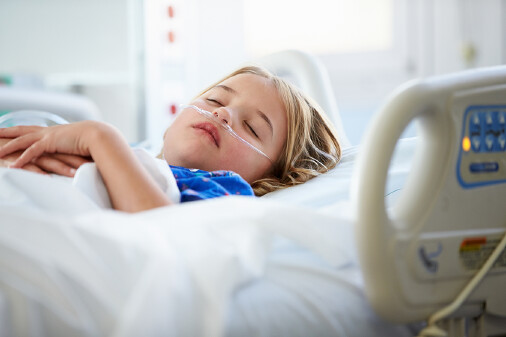 Kind liegt in einem Krankenhausbett mit einem Sauerstoffschlauch in der Nase