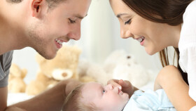 Mutter und Vater schauen auf Baby herab