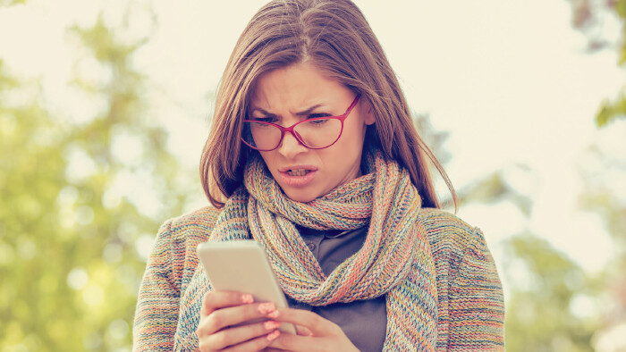 © Feodora, stock.adobe.com Frau blickt verwundert auf ihr Handy