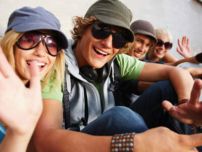4 Jugendliche, die fröhlich sind, 3 von ihnen tragen Sonnenbrillen
