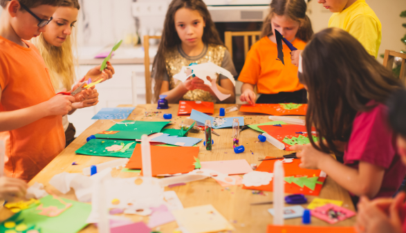 Eine Gruppe Kinder bastelt an einem Tisch mit Papier.