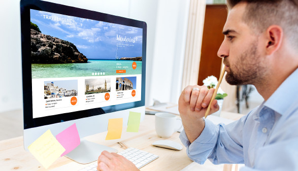 Junger Mann schaut sich Website eines Reiseportals an