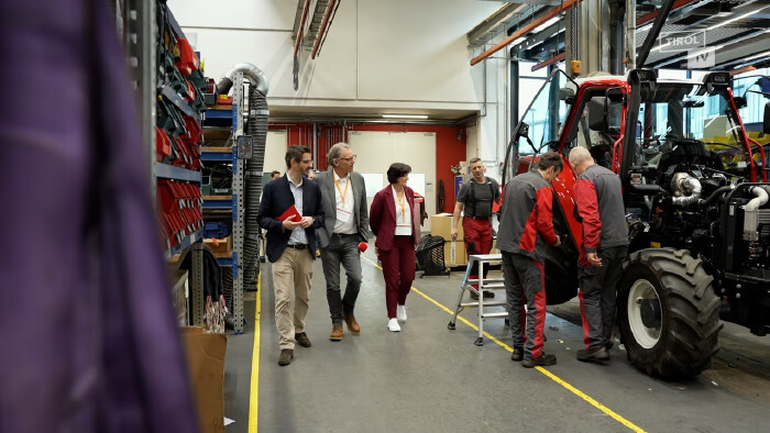 AK Vizepr&auml;sidentin Andrea Ager mit Moderator Hubert Trenkwalder besichtigt das Traktworenwerk Lindner, drei Herren beim Werkeln an einem Traktor 