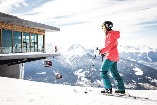 Skifahrerin auf der Bergstation der Patscherkofelbahn mit Blick Richtung Liftstation, im Hintergrund Bergkulisse