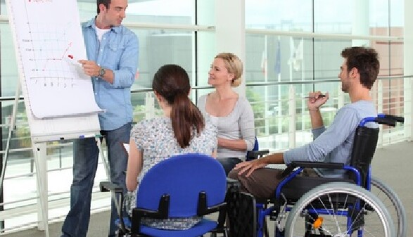 Junger Mann im Rollstuhl nimmt an einer Besprechung teil