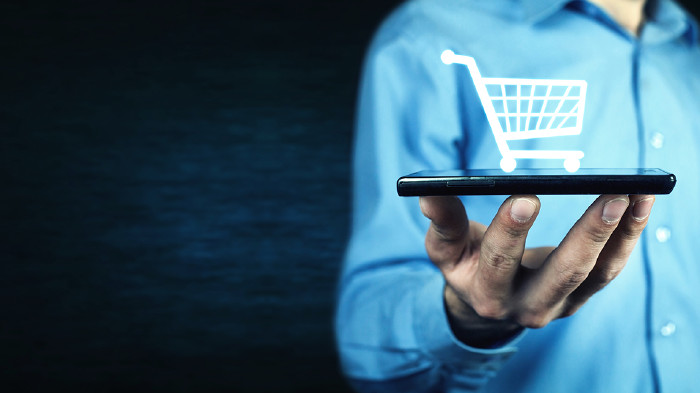 © andranik12/adobe.stock.com Mann hält Handy in der Hand mit Einkaufswagensymbol © andranik12/adobe.stock.com