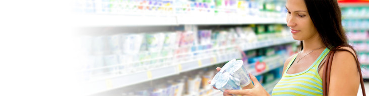 Frau steht im Supermarkt und prüft Joghurt