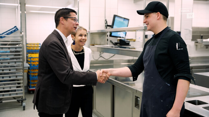 AK Vizepräsident schüttelt in der Küche des Naturhotels Waldklause einem Lehrling, der Landessieger bei den TyrolSkills wurde, die Hand