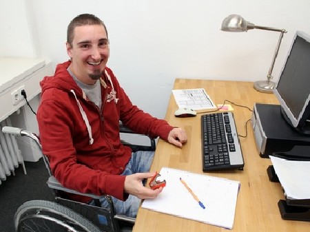 Junger Mann im Rollstuhl bei der Arbeit