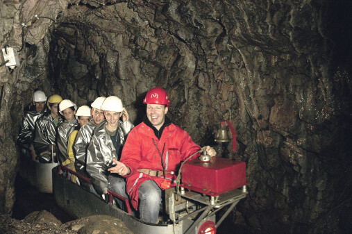 Mehrere Personen mit Helm fahren mit einem Zug in das Silberbergwerk Schwaz