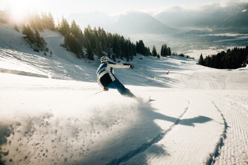 Skifahrer zieht seine Schwünge auf der leeren Piste, Blickrichtung talwärts