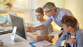 Lehrer erklärt Schüler etwas und zeigt auf den Bildschirm